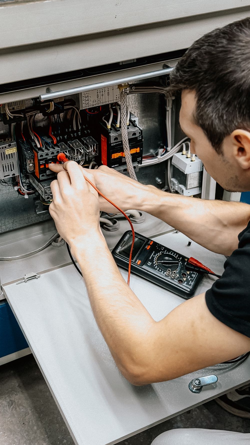 Controls engineer testing wiring inside an electrical control panel